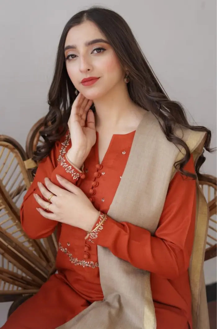 Woman wearing a red outfit with a beige scarf, sitting on a wooden chair.